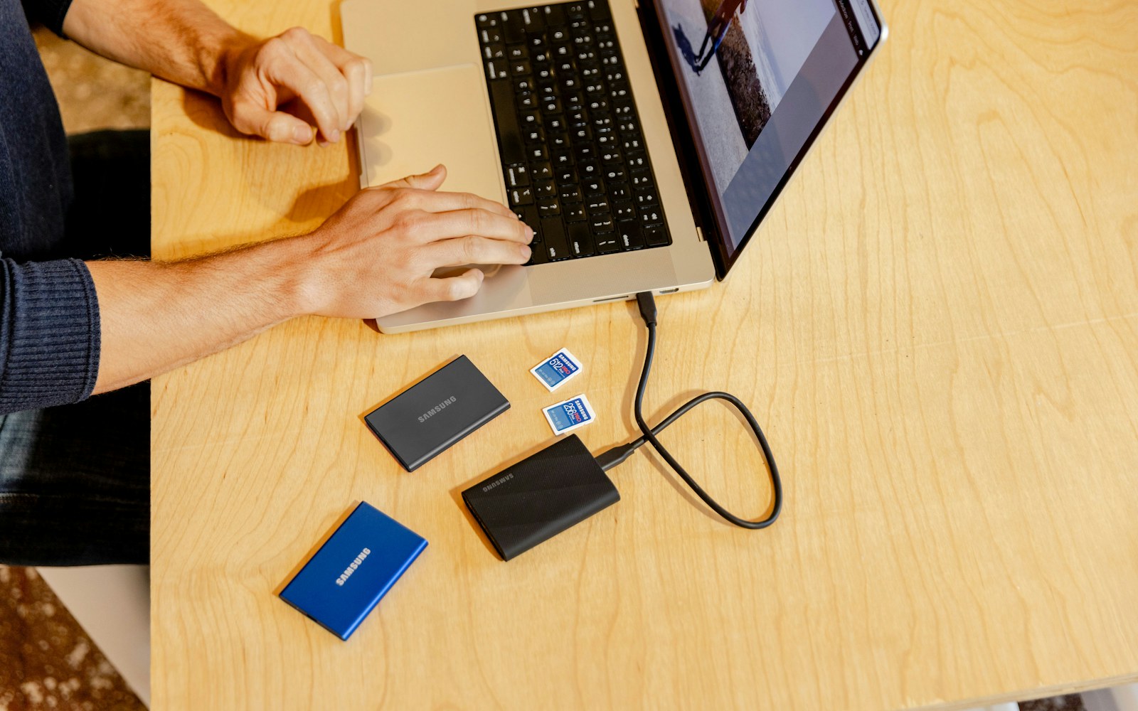Person working at a laptop with portable storage nearby