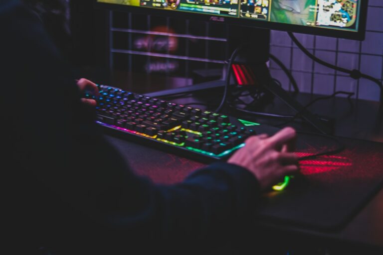 Hands using a gaming mouse and illuminated keyboard