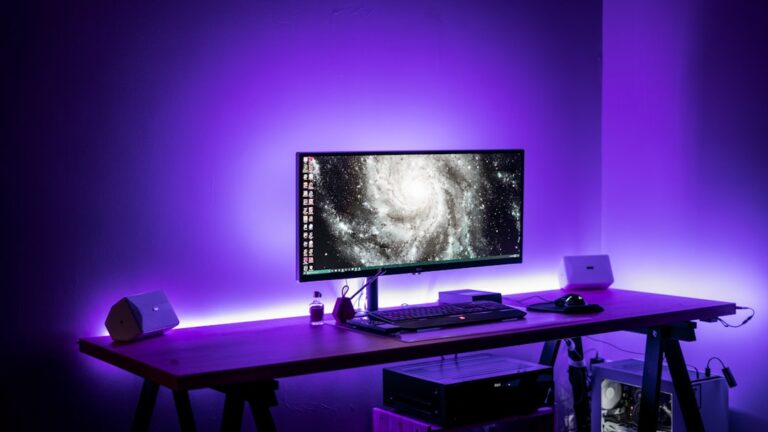 Wide desktop workstation with monitor, speakers and purple lighting